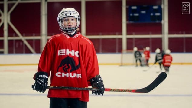 Detail: Junger Eishockeyspieler im roten Dress wartet auf der Eisfläche